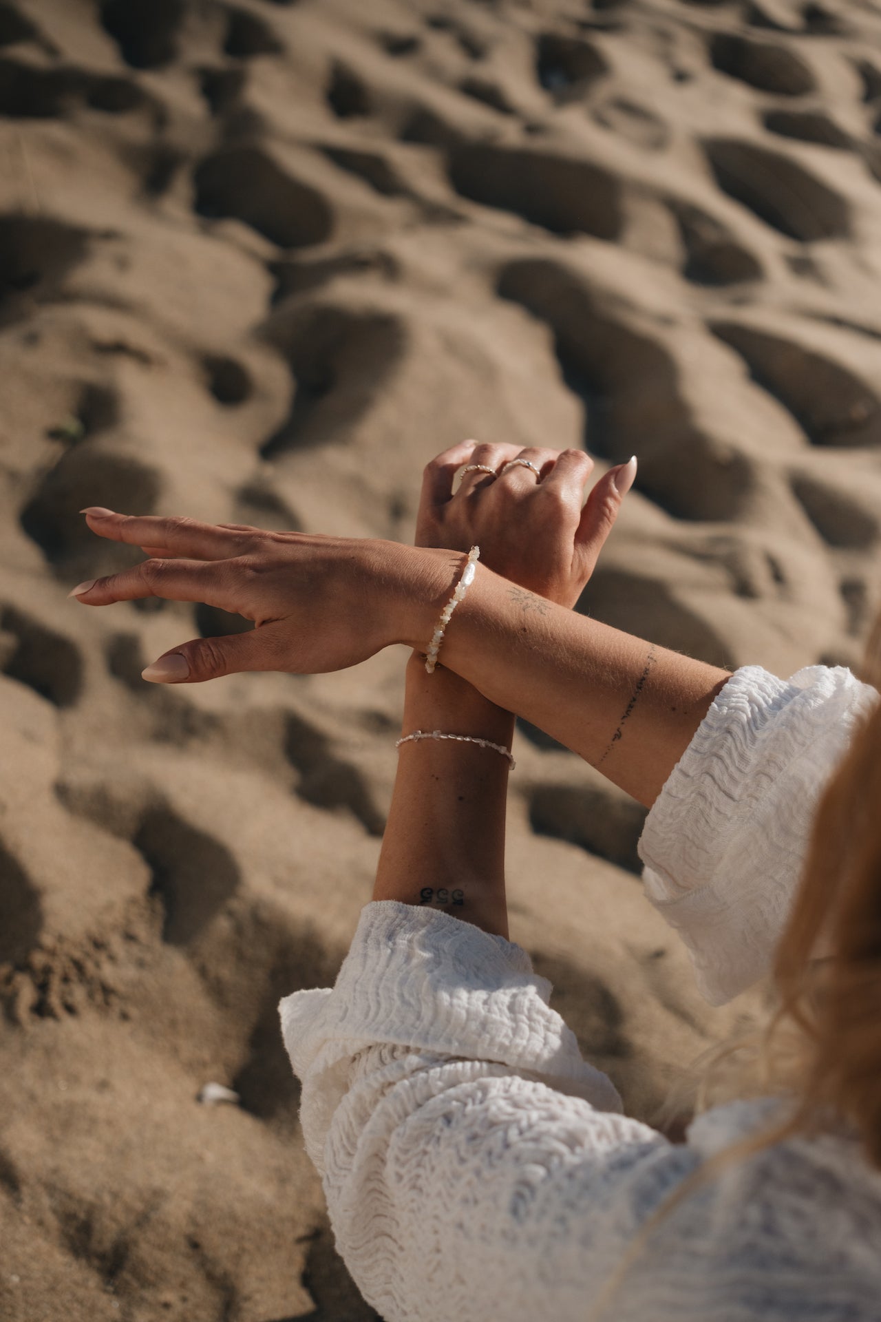 Armband aus Opalsteinen TRANSLUCENT SEA über Sand getragen