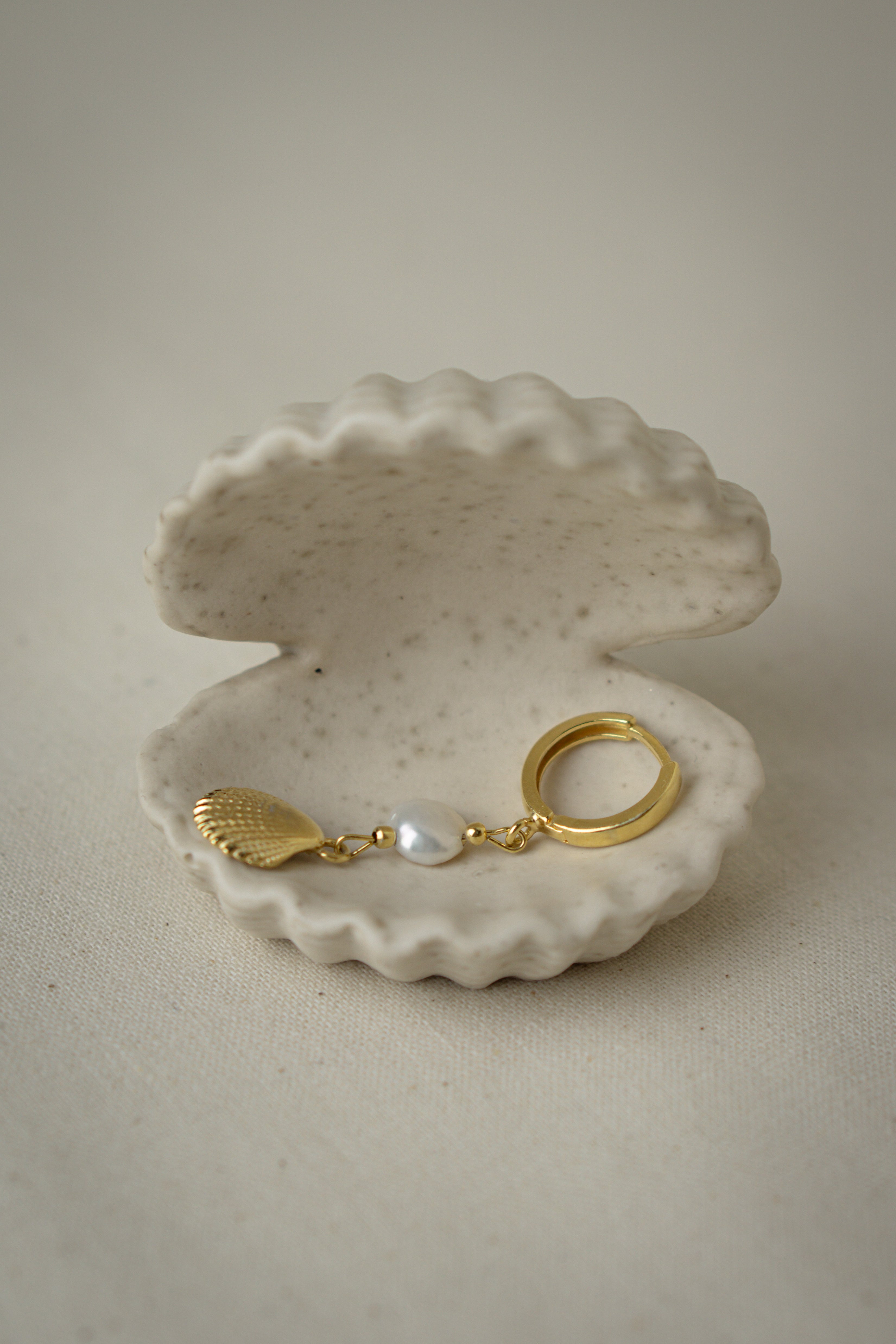 Creolen Ohrringe mit Muschelanhänger MAGIC SEA einzelner Ohrring liegend in einer Muschelschale aus Jesmonit