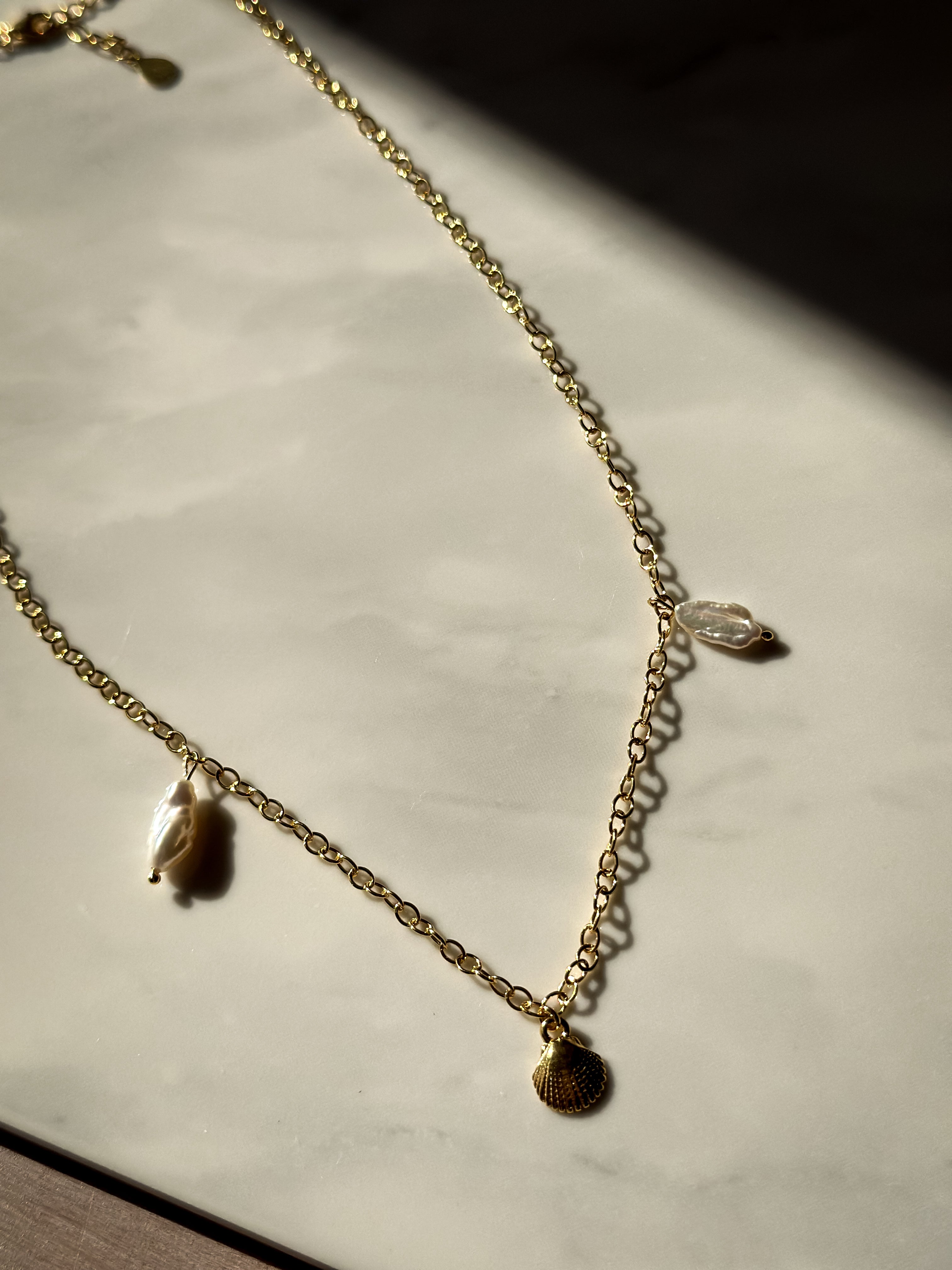 Kette UNDERWATER LOVE Flatlay Foto auf Marmor in der Sonne