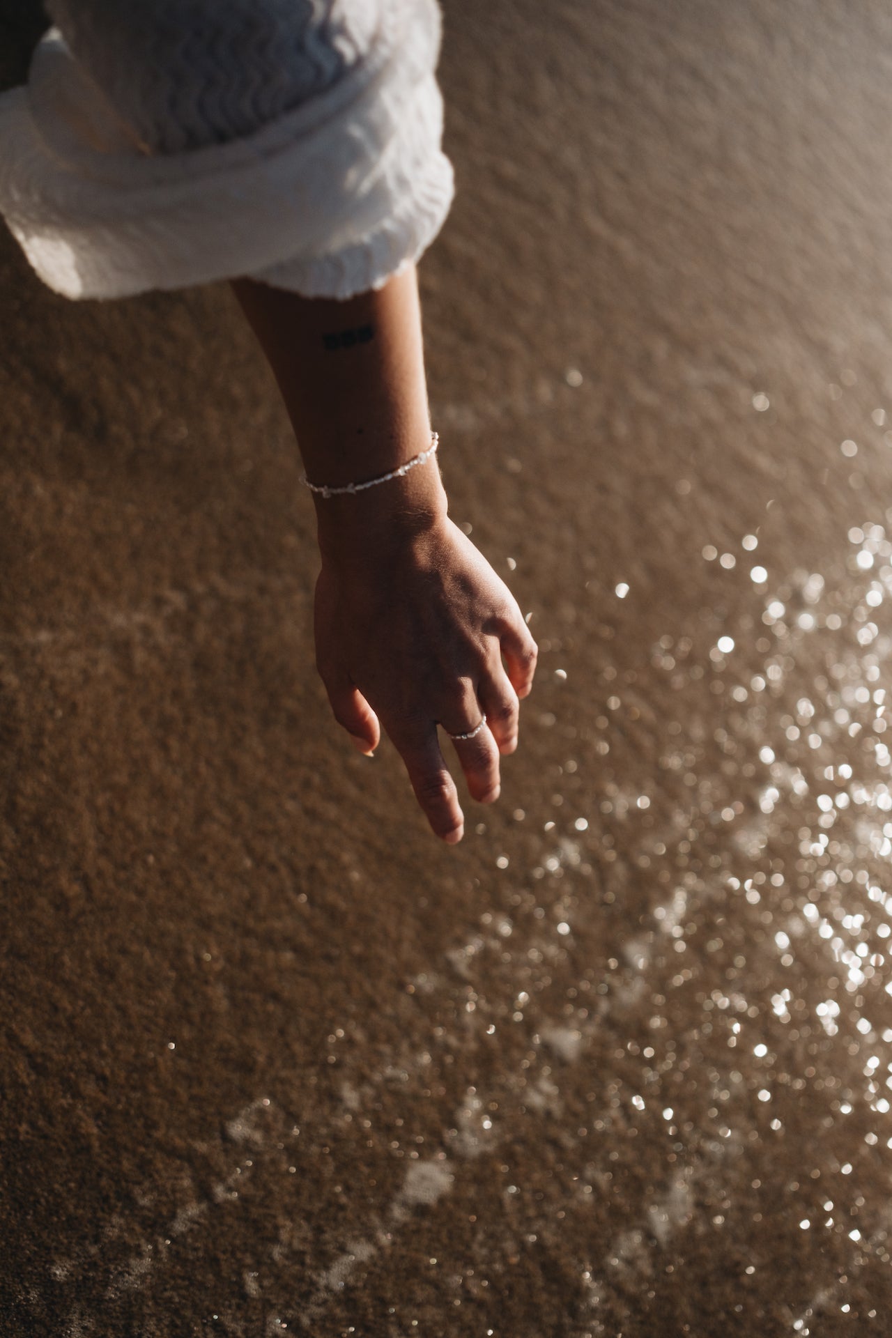 Perlenarmband BLUE MOON getragen über funkelnden Wasserreflektionen