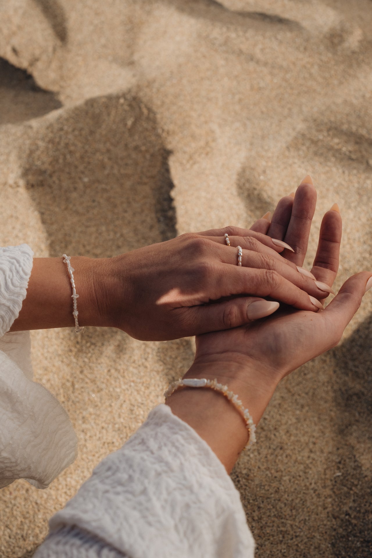Perlenarmband BLUE MOON Nahaufnahme Tragebild mit beiden Händen über Strandsand