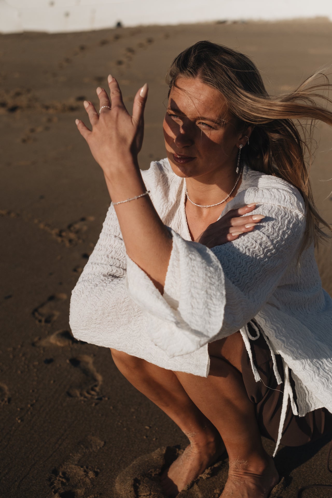 Perlenkette|Choker BLUE MOON im Set mit dem passenden Armband getragen von Model am Strand, das von Sonnenstrahlen geblendet wird