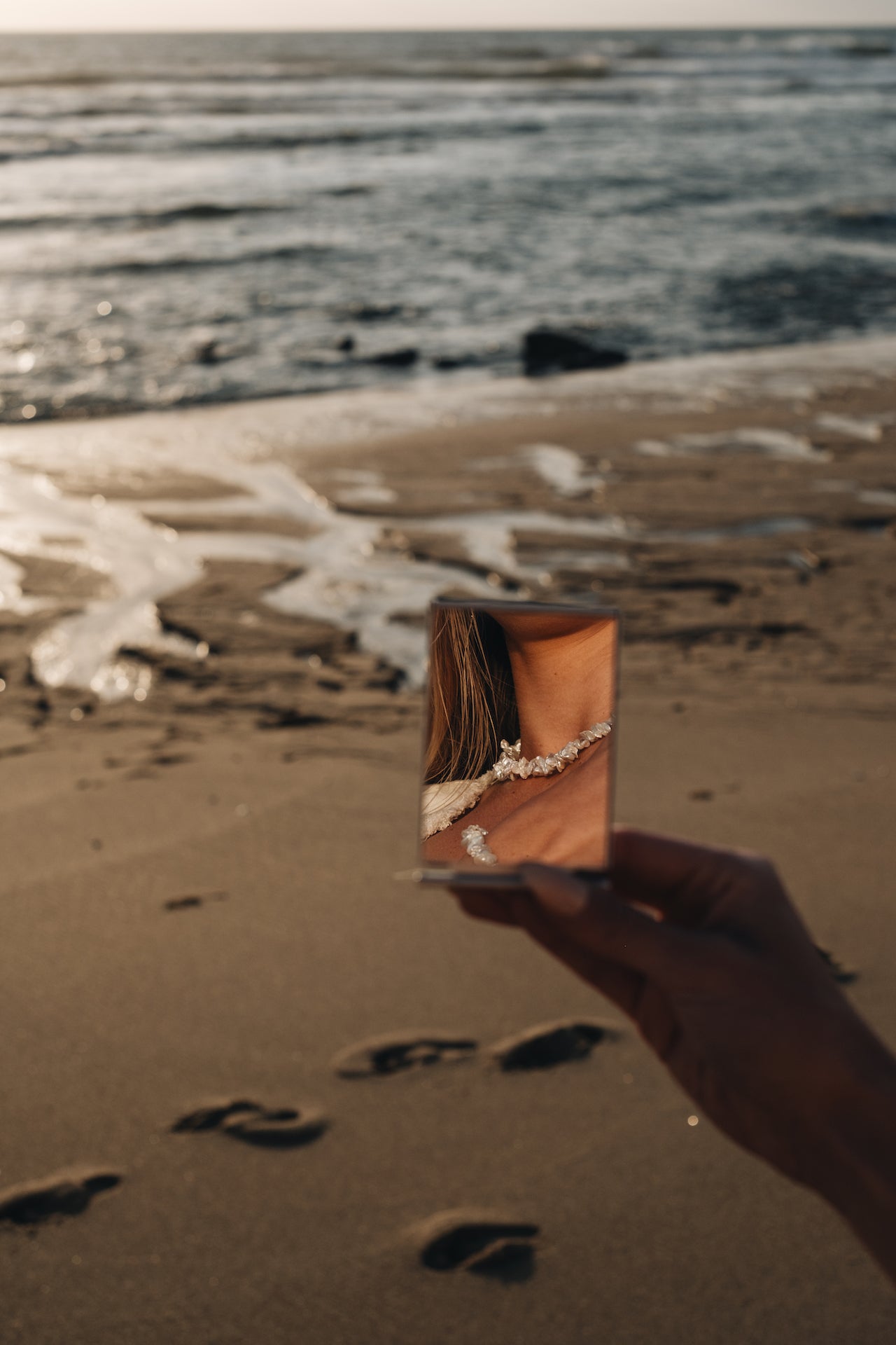 Perlenkette HAWAIIANDREAM Spiegelung eingefangen in einem Taschenspiegel mit Strand im Hintergrund