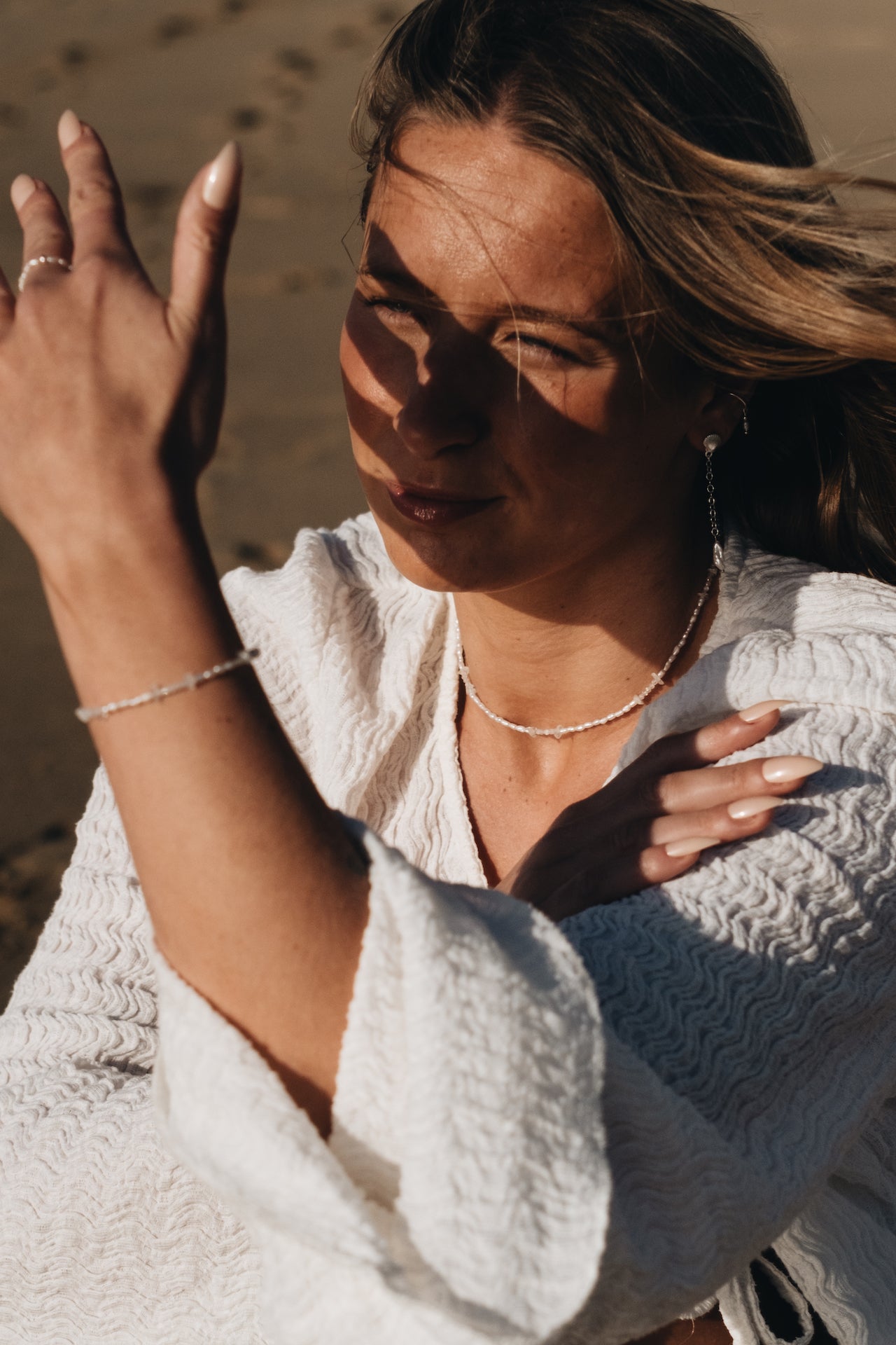Earcuff BASIC SEA mit Süßwasserperle getragen von weiblichen Model am Strand